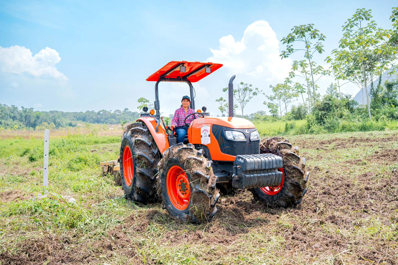 Agricultor al volante de un tractor Kubota en un terreno de cultivo