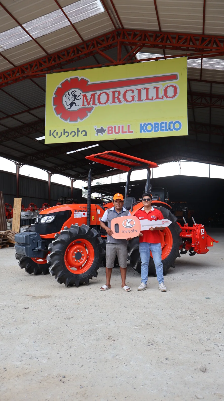 Clientes junto a un tractor y una llave de entrega en las instalaciones de Morgillo